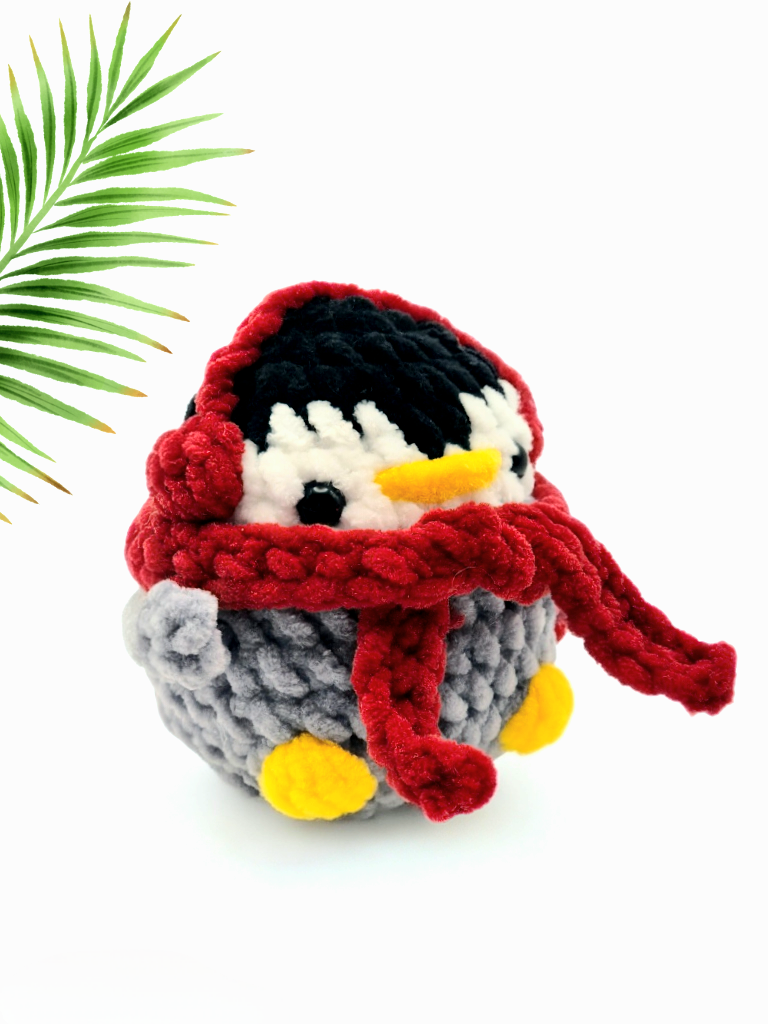 Iggy the penguin crochet kit toy made using plush chenille yarn, wearing a red scarf and earmuffs
