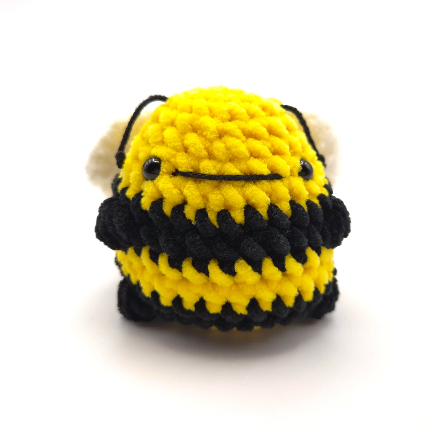 Crocheted bee toy with black and yellow stripes on a white background