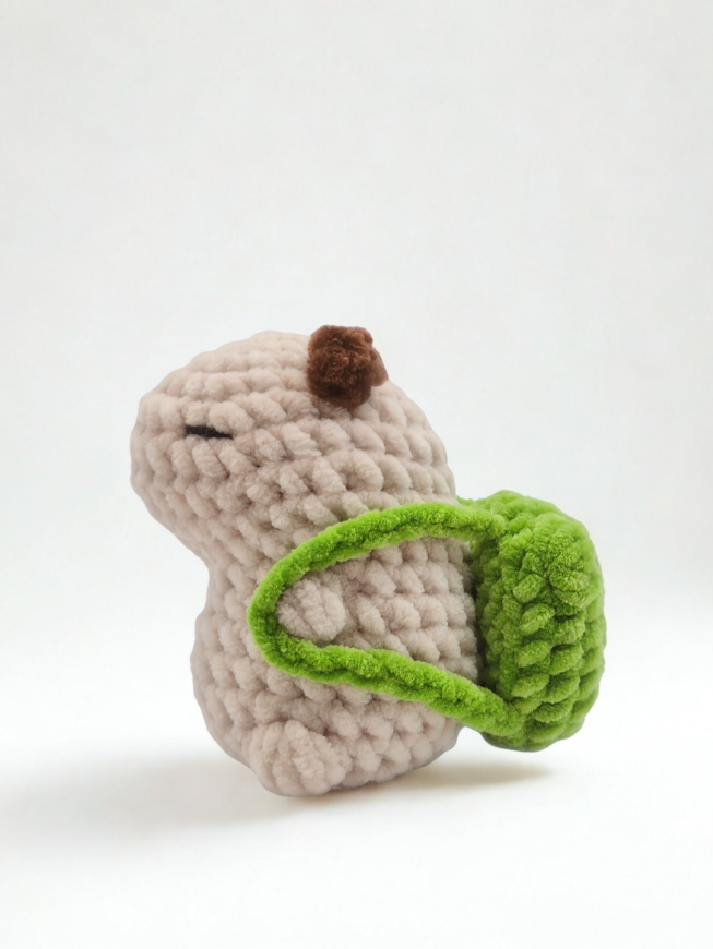 Mizu the crochet capybara wearing a frog backpack 