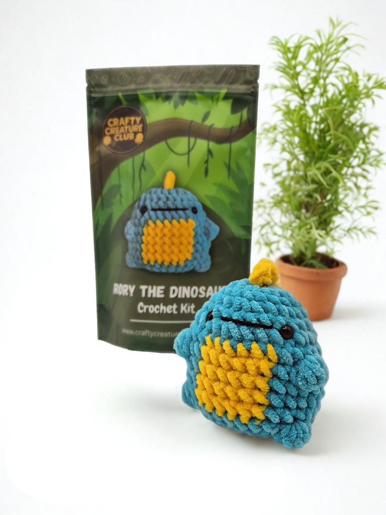 Rory dinosaur crochet kit shown with packaging and finished blue plush dinosaur